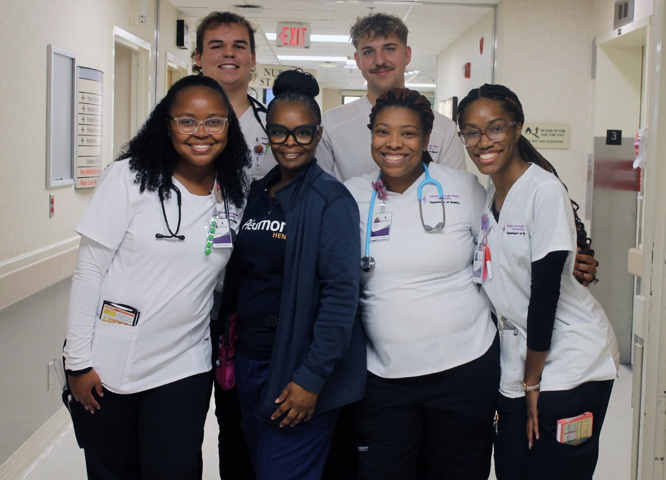5 smiling MGA nursing students surrounding Troya Thomas